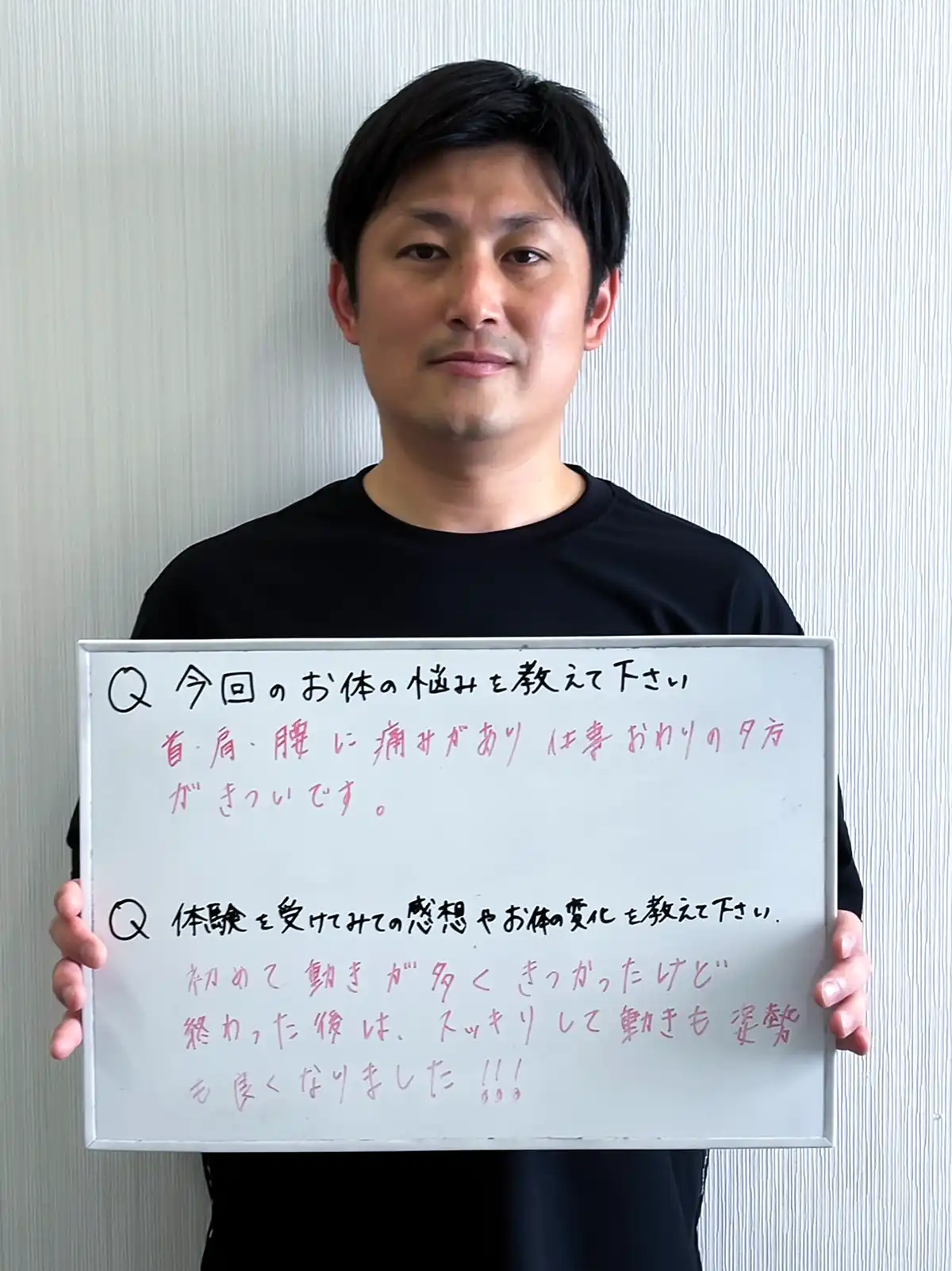 感想を書いたホワイトボードを手に持つ男性患者